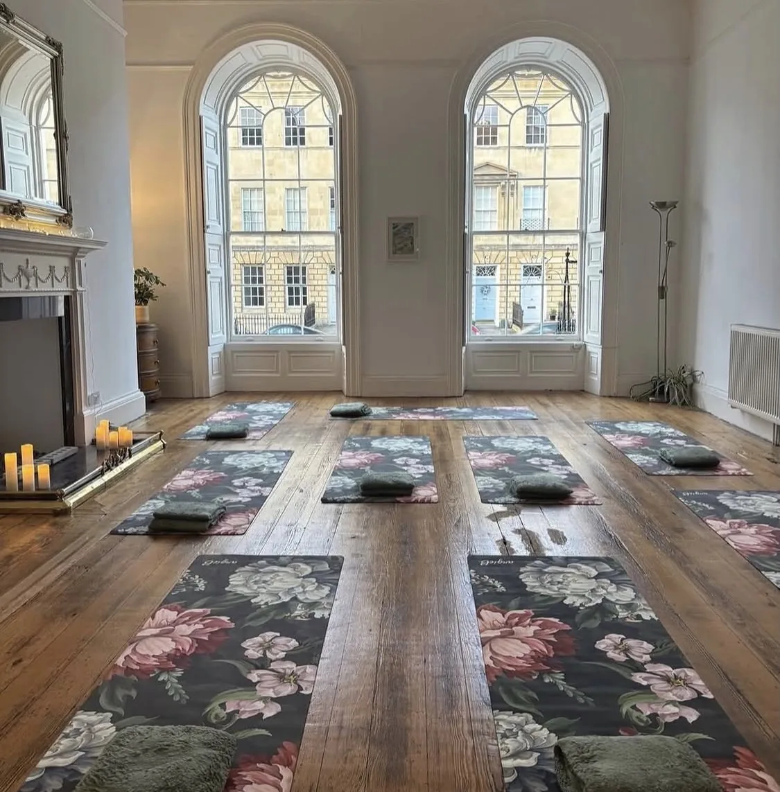 The Artpad event space set up for a yoga class, with mats and bolsters laid out on a wooden floor beneath two tall arched Georgian windows
